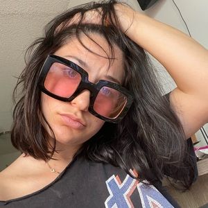 Elton John style oversized sunglasses. Pink lenses with black frames.